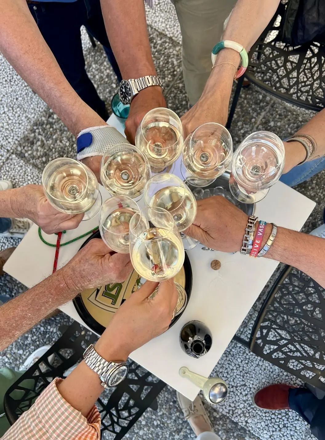 Anstoßen mit Sektgläsern auf einer Terrasse in Gargnano am Gardasee, umgeben von Armbändern und Uhren bei der SBF-See-und-Binnen-Ausbildung.
